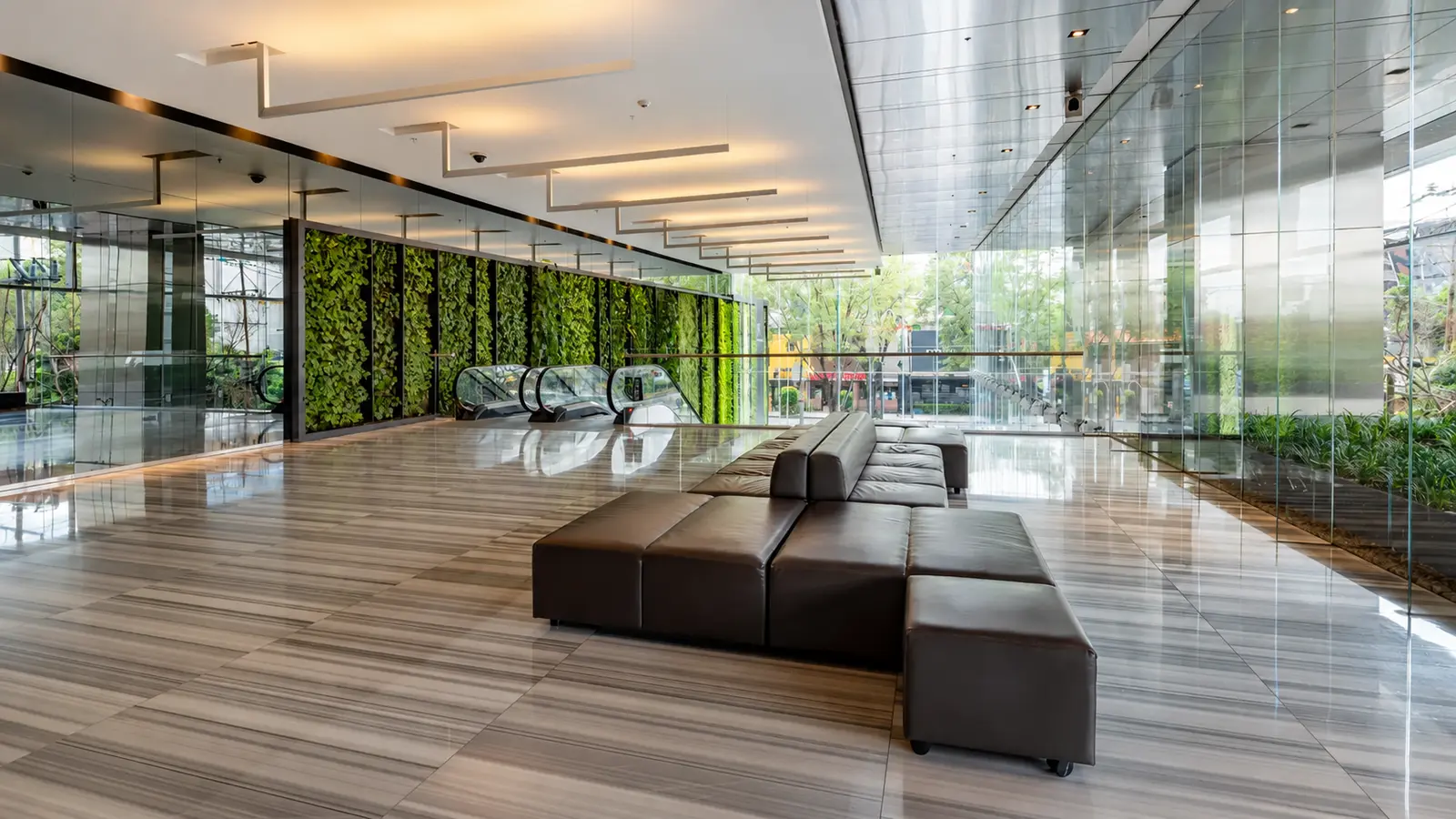 Vestíbulo corporativo con muro verde y escaleras eléctricas